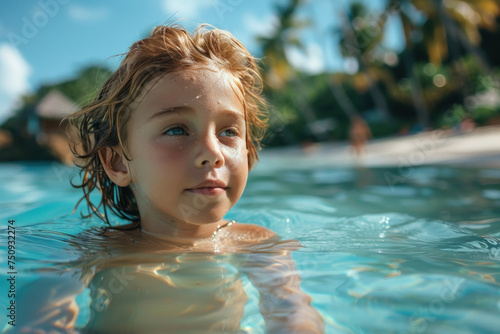 Caucasian child boy swim on tropical sea against the background of palm trees.