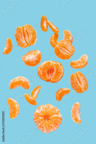 Flying sweet peeled mandarins on blue background