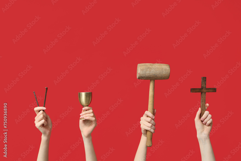 Female hands with wooden cross, mallet, cup and nails on red background. Good Friday concept Female hands with wooden cross, mallet, cup and nails on red background. Good Friday concept
