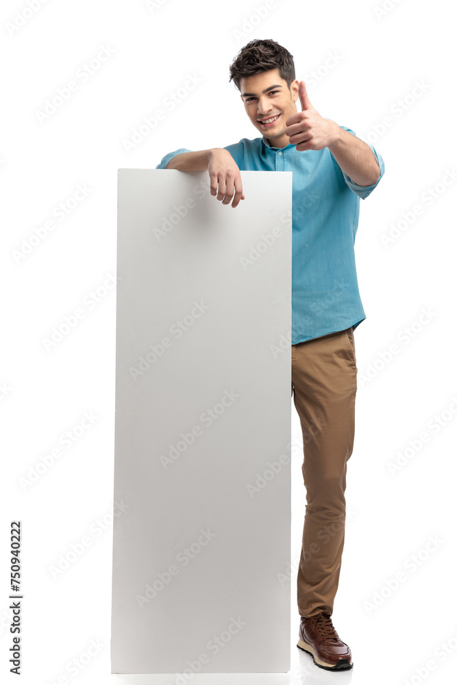 casual man making thumbs up sign while holding billboard casual man making thumbs up sign while holding billboard