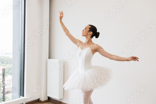 Young Caucasian ballet dancer practice wearing white swan skirt in studio, active lifestyle. Ballet student practicing classical dance pas in studio before performance.
