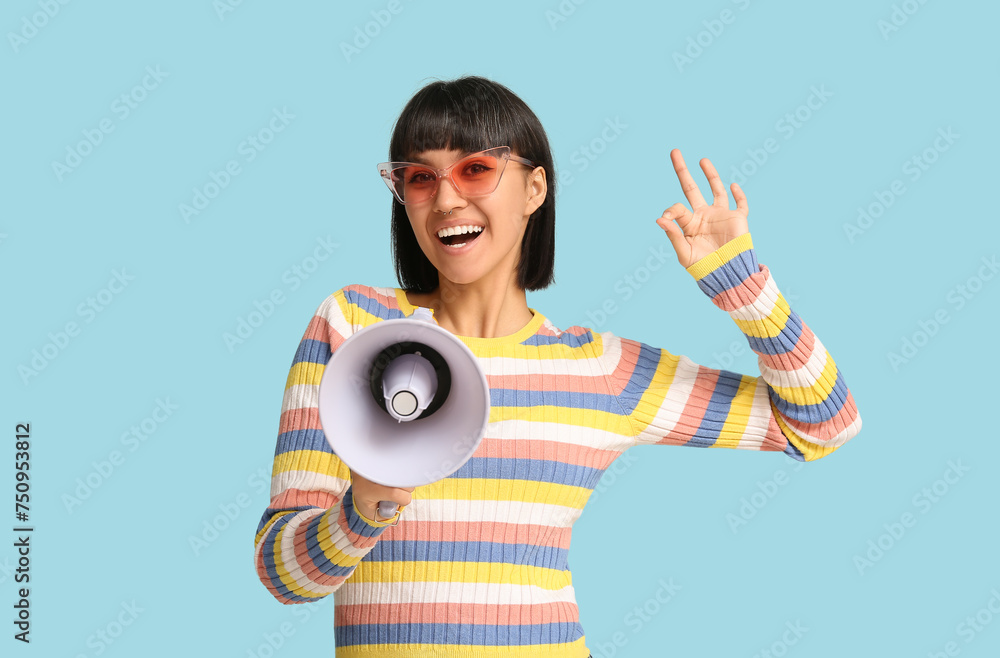 Young woman with megaphone showing OK on blue background Young woman with megaphone showing OK on blue background