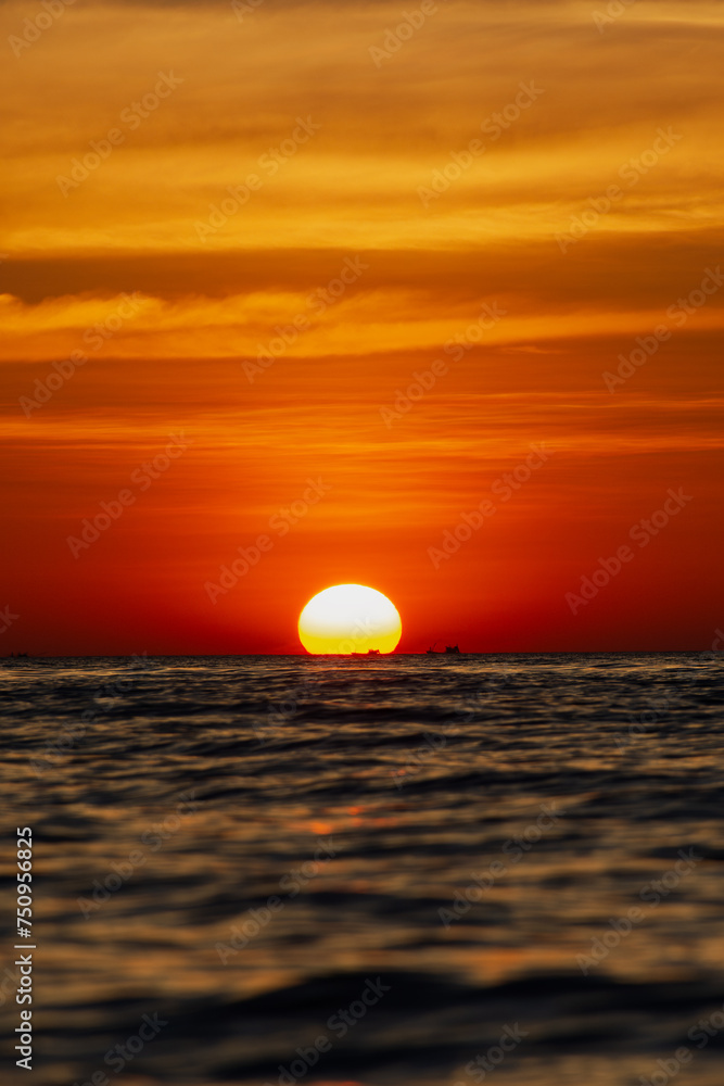 the big sun sets behind the horizon, a beautiful sea sunset. view low over the water. Bright red, orange sky over the ocean