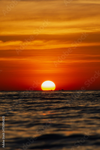 the big sun sets behind the horizon, a beautiful sea sunset. view low over the water. Bright red, orange sky over the ocean © Konstantin
