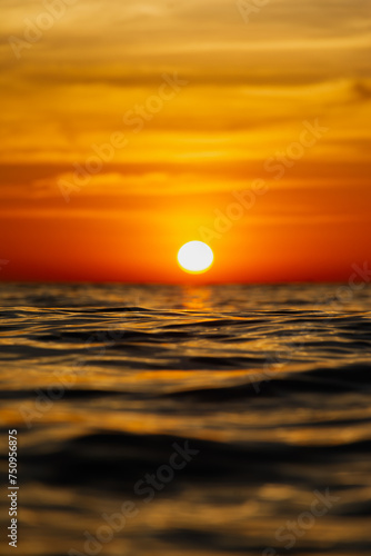 Fototapeta Naklejka Na Ścianę i Meble -  sun sets behind the horizon, a beautiful sea sunset. view low over the water. Bright red, orange sky over the ocean