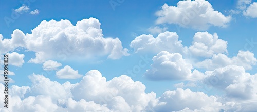 A commercial airplane is seen soaring through a vibrant blue sky filled with fluffy white clouds. The aircraft appears small against the expansive sky as it travels to its destination.