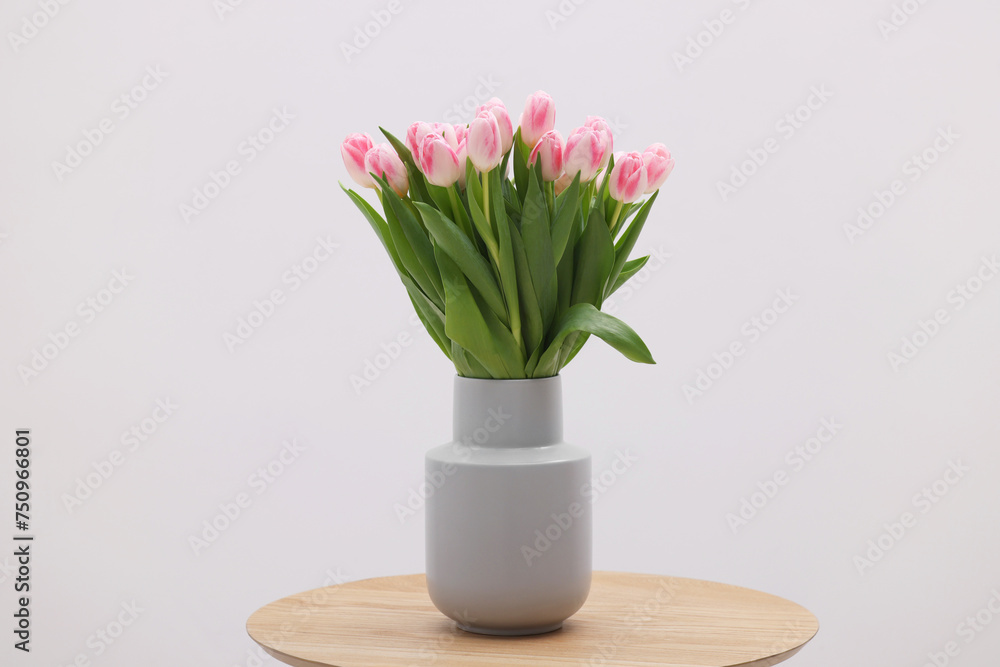 Beautiful bouquet of fresh pink tulips on table against light background