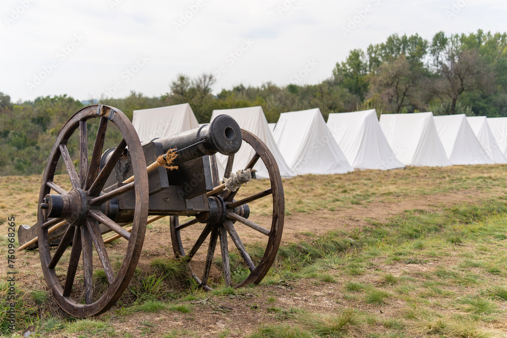 19th century Hungarian cannon in front of a military camp made of white tents