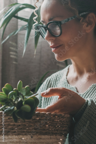 One adult woman relaxing at home in indoor gardening leisure activity alone with green succulenta plants. Smiling expression portrait female people and nature concept lifestyle. House garden inside photo