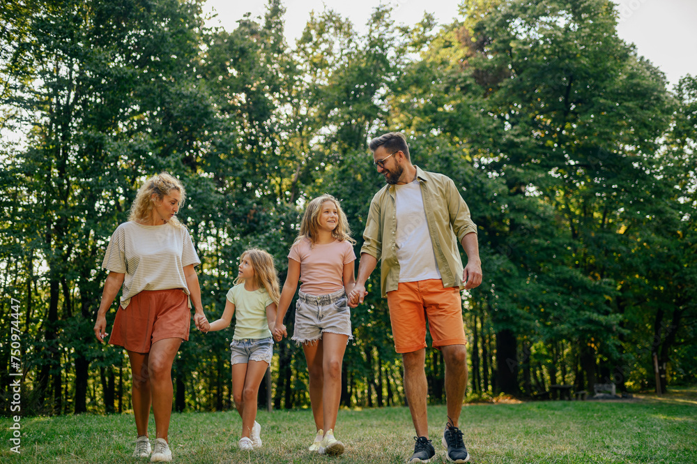 Obraz premium A cheerful loving family is holding hands and going for a walk in nature.