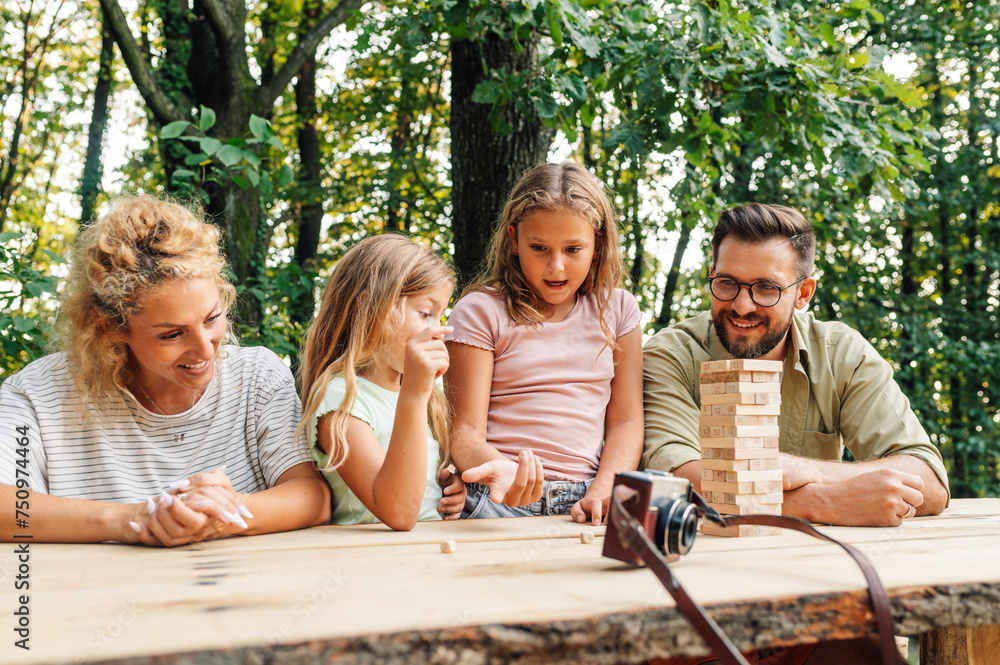 Fototapeta premium A playful girls playing jenga game with parents in nature.