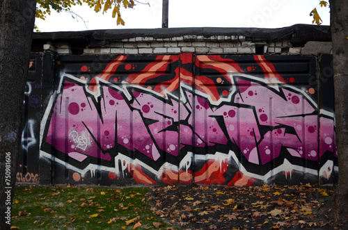 The old wall decorated with paint stains in the style of street art culture. Colorful background of full graffiti painting artwork with bright aerosol outlines on wall. Colored background texture