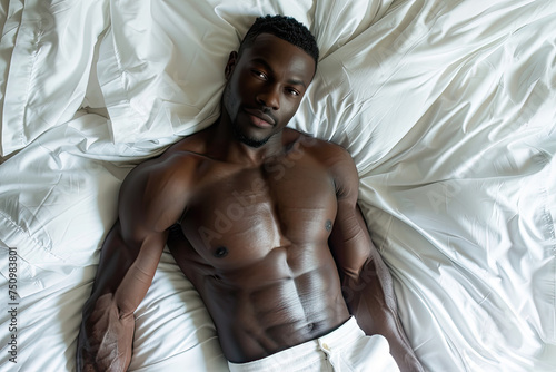 portrait of shirtless muscular young black man in bed