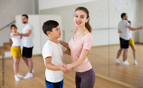 Mother and young son learning to dance waltz during group family classes.