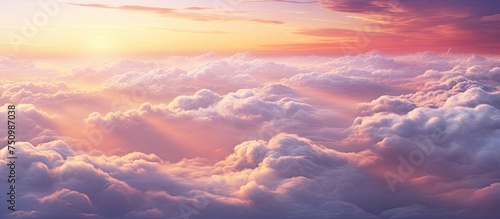 The sun is breaking through a layer of clouds in the sky during a gorgeous sunset cloudscape viewed from above. Sunlight streams through the clouds creating a dramatic and beautiful scene.