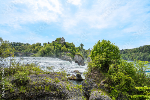 Tourists watch the massive waterfalls below Laufen Castle at the Rhine Falls from the rocks. Rhine Falls, Neuhausen am Rheinfall, Schaffhausen, Switzerland.