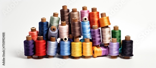 A collection of colorful spools of thread neatly arranged in a pile, placed side by side on a plain white background. The spools vary in size, color, and material, creating a visually appealing