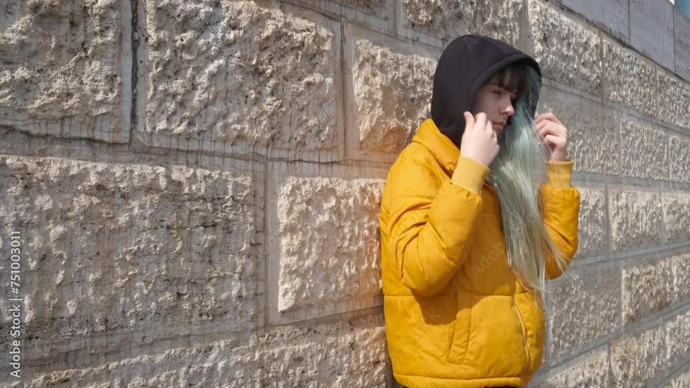 A sad teenage girl stands against the wall. The concept of loneliness in adolescence. A sad teenage girl stands against the wall. The concept of loneliness in adolescence.