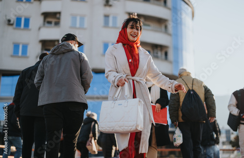 A cheerful woman in a red scarf and white coat joyfully walks with coworkers through a bustling city street, embodying urban lifestyle and professional camaraderie.
