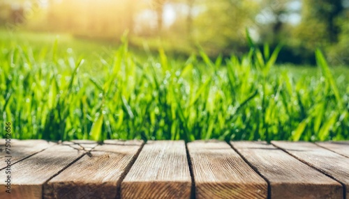 beautiful spring natural background with green fresh juicy young grass and empty wooden table in nature morning outdoor beauty bokeh and sunlight