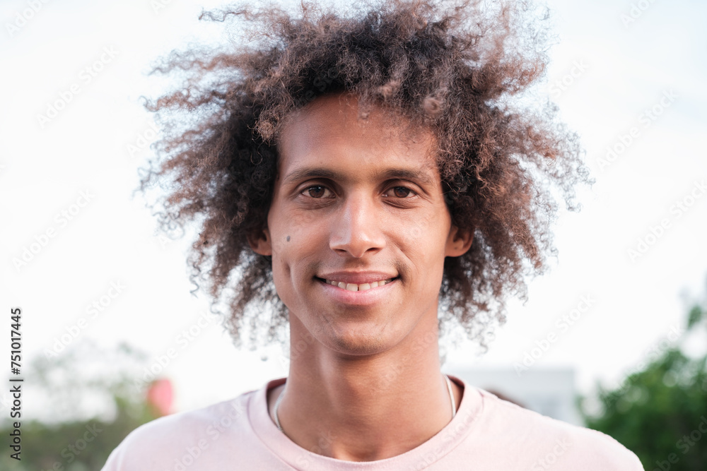 Young man with curly hair smiling outdoors close-up. Concept: lifestyle, fun Young man with curly hair smiling outdoors close-up. Concept: lifestyle, fun