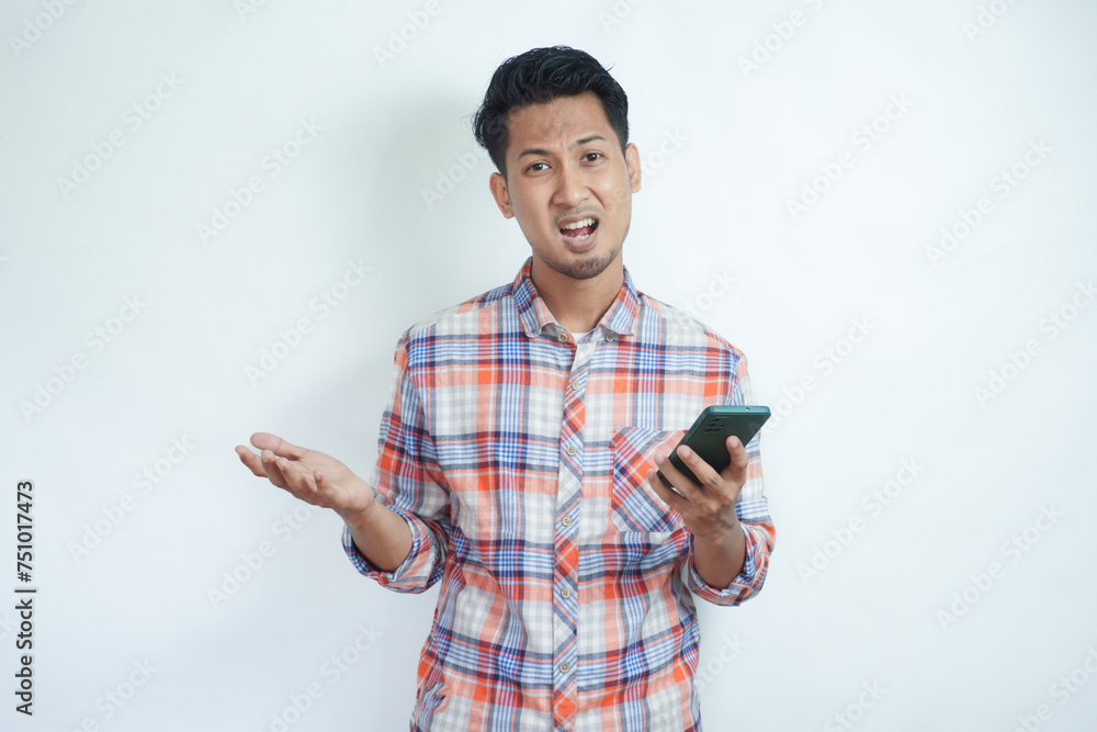 Adult Asian man showing disappointed expression while holding mobile phone Adult Asian man showing disappointed expression while holding mobile phone