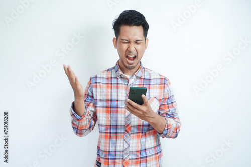 Adult Asian man showing rage expression when looking to his cellular phone photo