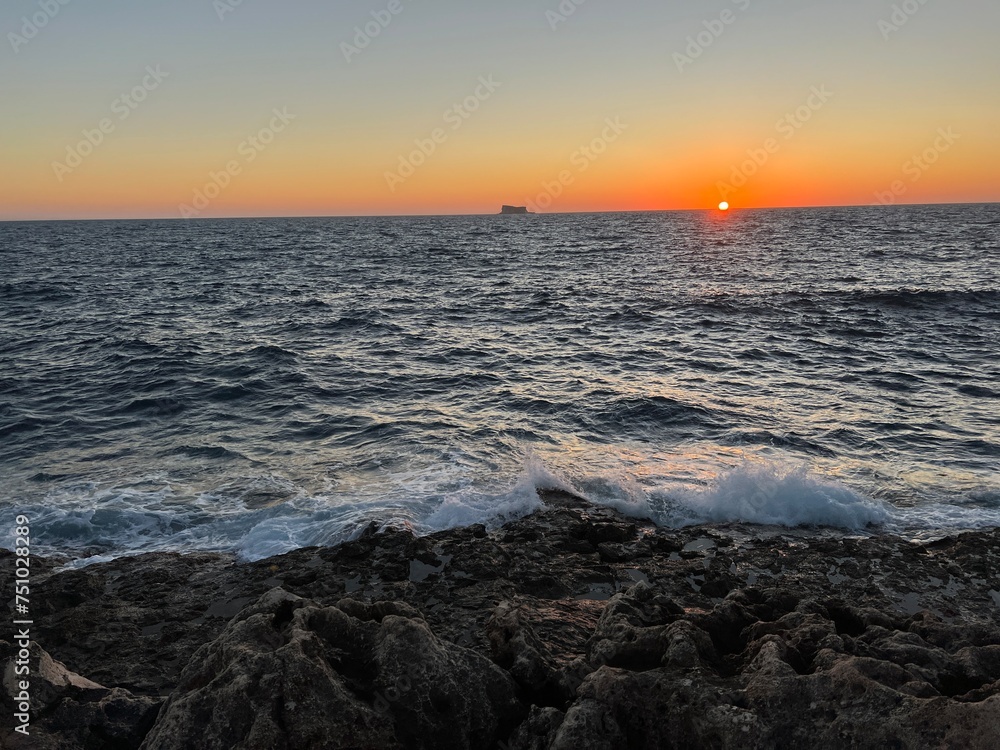 Sunset on the Mediterranean Sea with a far away seen island in the distance at Malta 