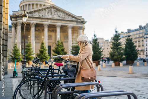 Happy woman parking bike on street during Xmas holidays photo