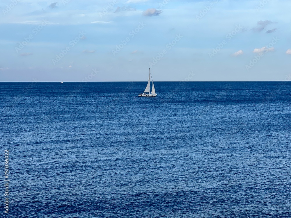 View of the sea and white sailboat on the horizon from the balcony on the promenade by the sea at Sliema  Malta