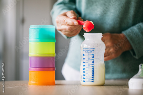 Old woman adding powder milk for baby in bottle 