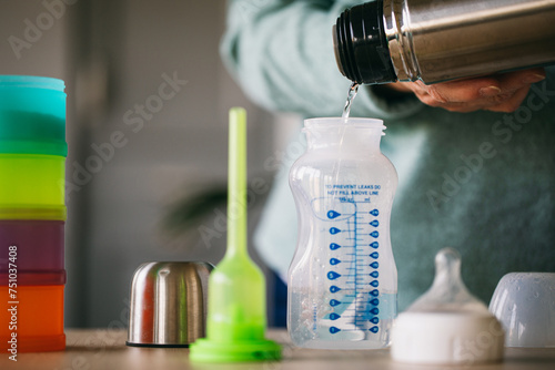 Old woman pouring hot water in baby bottle  photo
