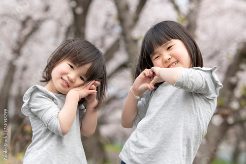 桜並木の公園で遊んでいる姉妹 © kai