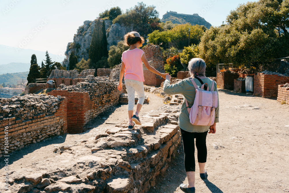 Kid and woman walking on ancient Greek ruines in Taormina, Sicily Kid and woman walking on ancient Greek ruines in Taormina, Sicily
