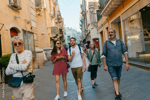 Group of tourists walking on crowded street of small touristic town photo