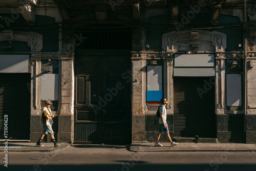 Young and old men walking on decadent old city in sunlight photo