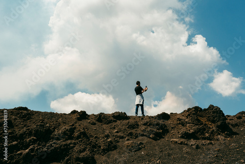 Anonymous tourist in Mount Etna taking pictures of volcano photo