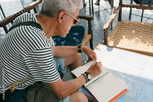 Senior man outdoors writing on notebook