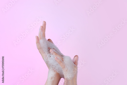 Hands washing gesture with foaming hand soap on pastel photo