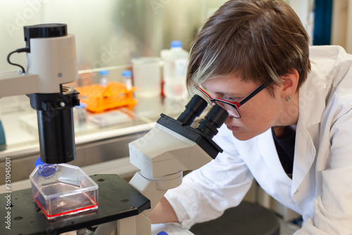 woman scientist looking at the microscope in a lab, research photo