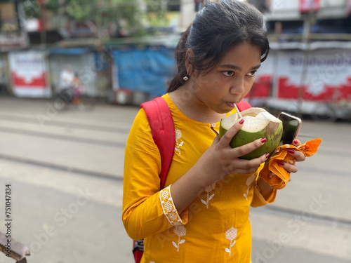 Teenage girl drinking green coconut water in the strret at outdoors photo