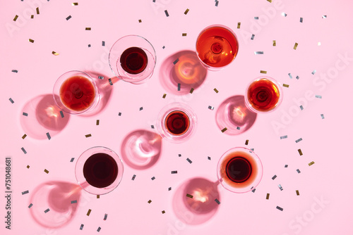 Different glasses with wine on pink background, top view photo