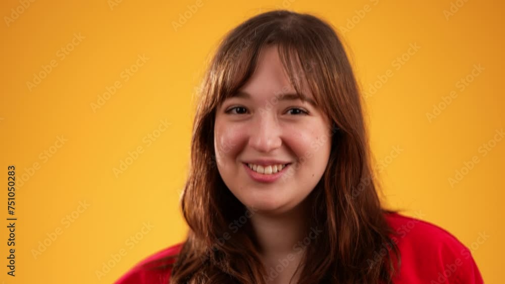 Young happy woman with brown hair wearing glasses and jacket blowing kiss as love gesture, isolated on yellow background with copy space in slow motion Young happy woman with brown hair wearing glasses and jacket blowing kiss as love gesture, isolated on yellow background with copy space in slow motion