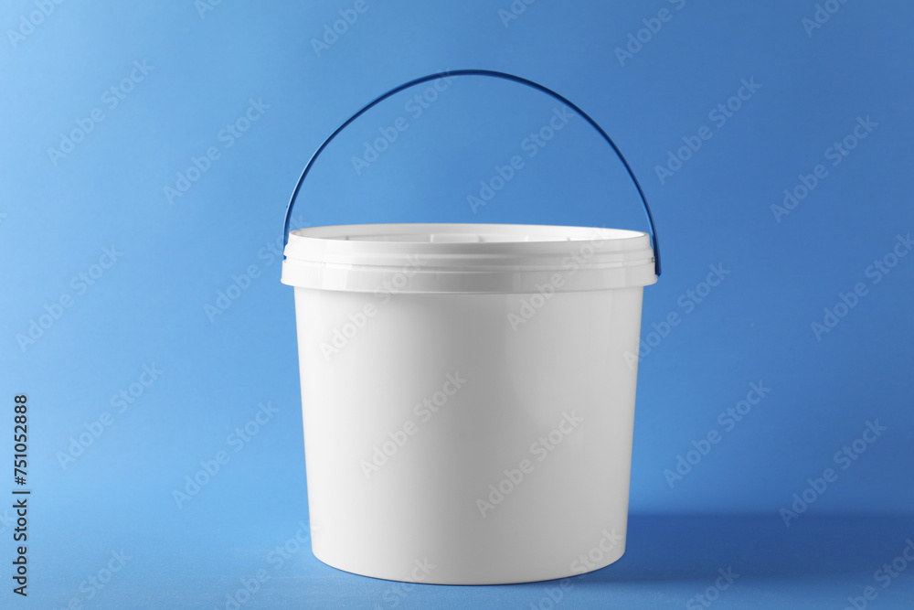 One plastic bucket with lid on light blue background - obrazy, fototapety, plakaty 