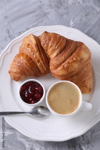 Tasty breakfast. Cup of coffee, fresh croissants and jam on grey table, top view