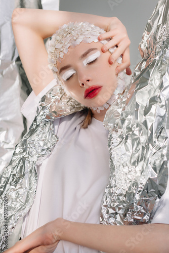 Extravagant woman with closed eyes near silver foil photo