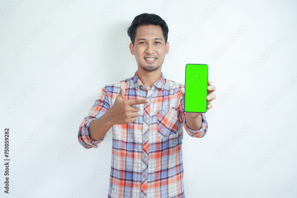 Adult Asian man smiling happy while showing green mobile phone screen and pointing on it Adult Asian man smiling happy while showing green mobile phone screen and pointing on it