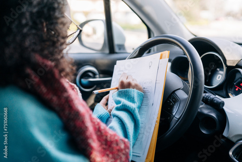 Crop woman writing in documents inside car