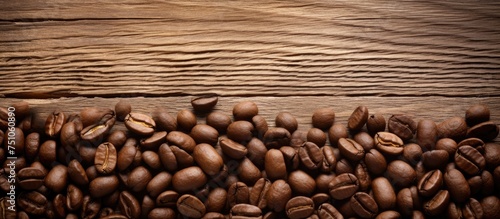 A collection of roasted coffee beans neatly stacked on a textured wooden table. The warm hues of the beans contrast against the rustic backdrop, creating a simple yet inviting scene. © pngking