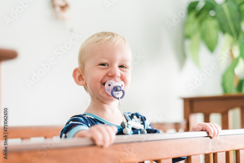 Portrait of Grinning Toddler Boy Smiling Out of Crib photo